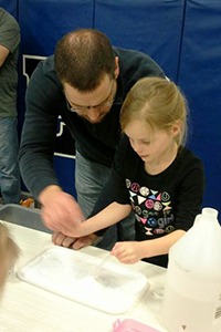 Father and daughter work at one of the science stations